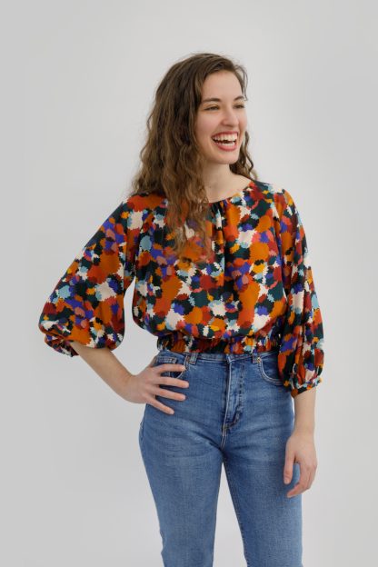 Woman wearing the Whitcomb Top sewing pattern from Sew Love Patterns on Fold Line. A top pattern made in cotton, linen, viscose, cupro, crepe and rayon fabrics, featuring ¾ length sleeves with gathered cuffs, hip length, and round neckline with gathered front.