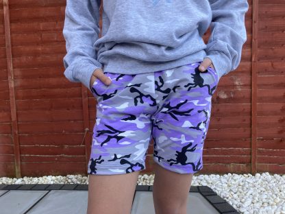 Girl wearing the Teen Girls' Shoreline Shorts sewing pattern from Waves & Wild on The Fold Line. A shorts pattern made in medium weight knit fabrics, featuring a mid-length leg, slash pockets and elasticated waist.