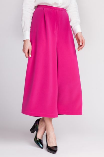Woman wearing the Mimosa Culottes sewing pattern from Named on The Fold Line. A culottes pattern made in non-stretch trousers fabrics, featuring a midi-length, high waist, wide legs, slanted front pleats, fly front zip fastening, slash side pockets and narrow waistband fastens with button and hook closure.