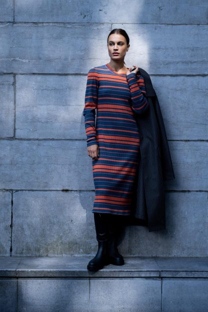 Woman wearing the Roya Dress sewing pattern from Fibre Mood on The Fold Line. A knit dress pattern made in jersey cotton, jersey viscose, jersey wool, jersey lyocell, or jersey bamboo fabrics, featuring long narrow sleeves with gathers at the sleeve head, round neck with neckband, and midi length.