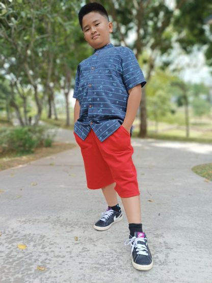 Boy wearing the Teen Boys' Shoreline Shorts sewing pattern from Waves & Wild on The Fold Line. A shorts pattern made in medium weight knit fabrics, featuring a below knee-length leg, slash pockets and elasticated waist.