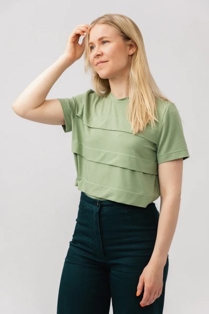 Woman wearing the Pleated Tee sewing pattern from Named on The Fold Line. A top pattern made in light jersey fabrics, featuring short sleeves, hip length, neck band, straight cut, and wide horizontal front pleats.