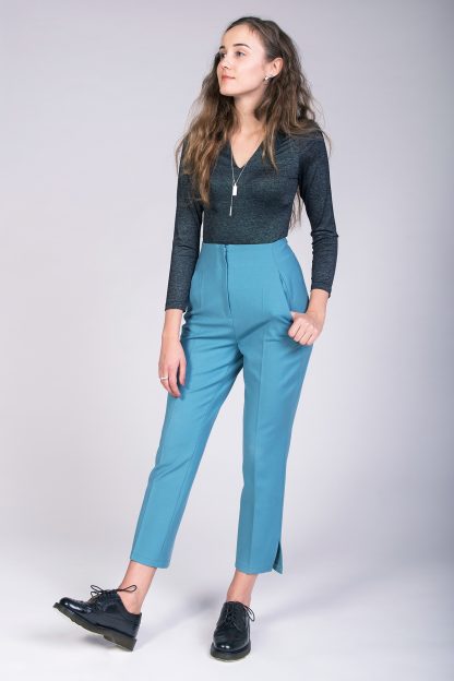 Woman wearing the Tyyni Cigarette Trousers sewing pattern from Named on The Fold Line. A trousers pattern made in light trousering or suiting fabrics, featuring a high-waist, straight legs, slim fit, in-seam side pockets, zip fly fastening, and cropped length with hem vents.