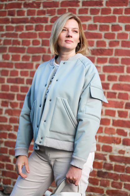 Women wearing the Arthur Bomber Jacket sewing pattern from Lenaline Patterns on The Fold Line. A bomber jacket pattern made in Jersey, quilted fabrics, chino, denim, jacquard, imitation leather, gabardine cotton, velvet, or softshell fabrics, featuring front bevelled patch pockets, flap pocket on left sleeve, raglan sleeves, topstitched seams, ribbed neckline, hem and cuff, and snap closure.