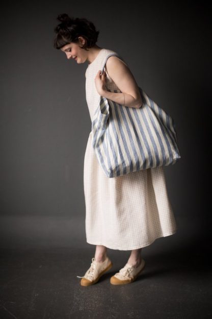 Woman holding the Orton Bag sewing pattern by Merchant and Mills. An oversized tote bag pattern made in oilskin, linen, denim, twill or corduroy fabric with three handle options.