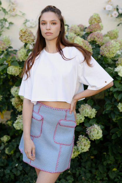 Woman wearing the Lilly Skirt sewing pattern from JULIANA MARTEJEVS on The Fold Line. A blanket stitch hand sewn skirt pattern made in wool loden fabrics, featuring a mini length, front patch pockets and snap side closure.
