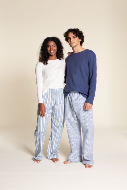Man and Woman wearing the Unisex PJ Pants sewing pattern from Wardrobe by Me on The Fold Line. A pyjama pant pattern made in cotton, silk or viscose fabrics, featuring an elastic and drawstring waist, no side seams, relaxed fit and full length leg.