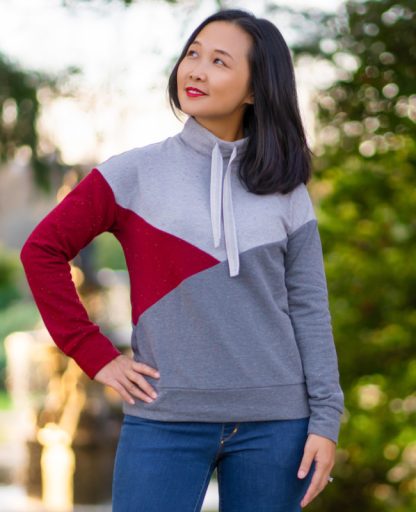 Woman wearing the Boalsburg Pullover sewing pattern from Itch to Stitch on The Fold Line. A pullover pattern made in brushed French terry, loop back French terry, sweatshirt fleece, fleece back jersey and interlock fabrics, featuring dropped shoulders, long sleeves with cuffs, funnel collar with optional drawstring and colour blocking.