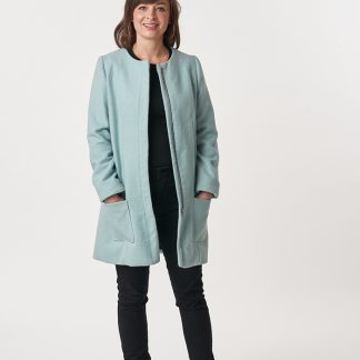 Woman wearing the Chloe Coat sewing pattern from Sew Over It on The Fold Line. A semi-loose coat pattern made in tweed, boucle, boiled wool, melton, jacquard or linen fabrics, featuring patch pockets, round neck, detachable scarf, either zipper or press stud closure and full length sleeves.