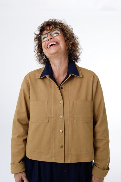 Woman wearing the Den Jacket sewing pattern from Chalk and Notch on The Fold Line. A jacket pattern made in canvas, corduroy, denim, flannel, linen, or twill fabrics, featuring an optional lining, topstitching, collar, fold-up cuff, centre front snap closure, cropped length, front patch pockets and large in-seam pockets.