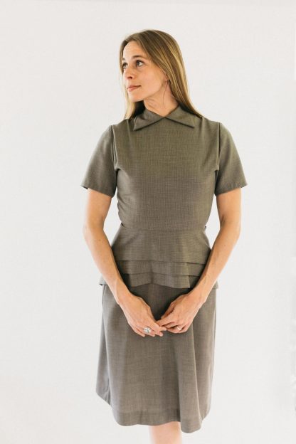 Woman wearing the 249 1930s Day Dress sewing pattern from Folkwear on The Fold Line. A dress pattern made in rayon, medium-weight silk, or microfibre fabrics, featuring a round neck with collar points, peplum, back zipper, dropped waistline, short sleeves, slightly flared skirt and knee length.