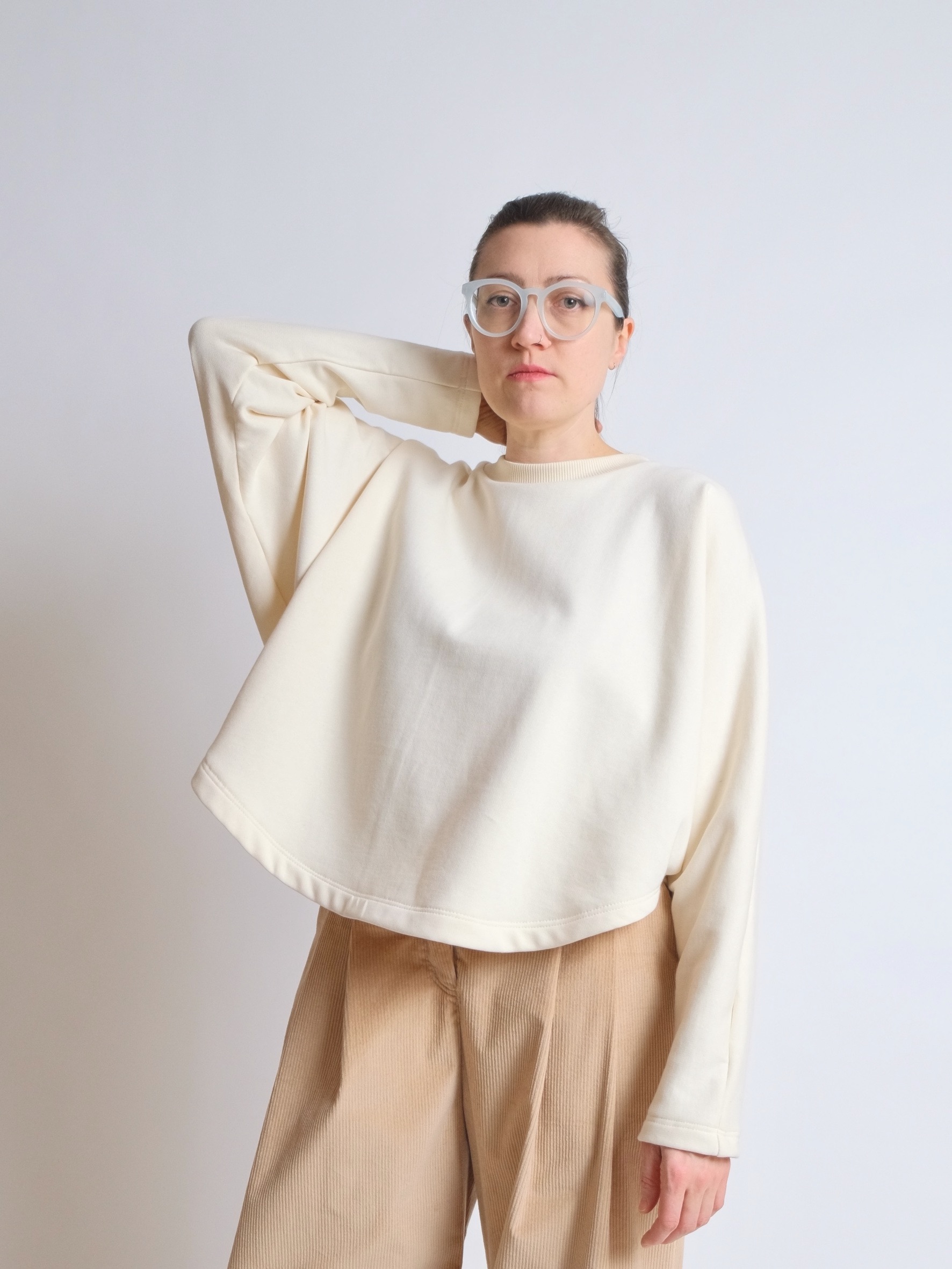 Woman wearing the ZW Jumper sewing pattern from Birgitta Helmersson on The Fold Line. A top pattern made in woven or knit fabrics, featuring an oversized fit, curved hem, full length slim sleeve, and crew neck with ribbed neck band.