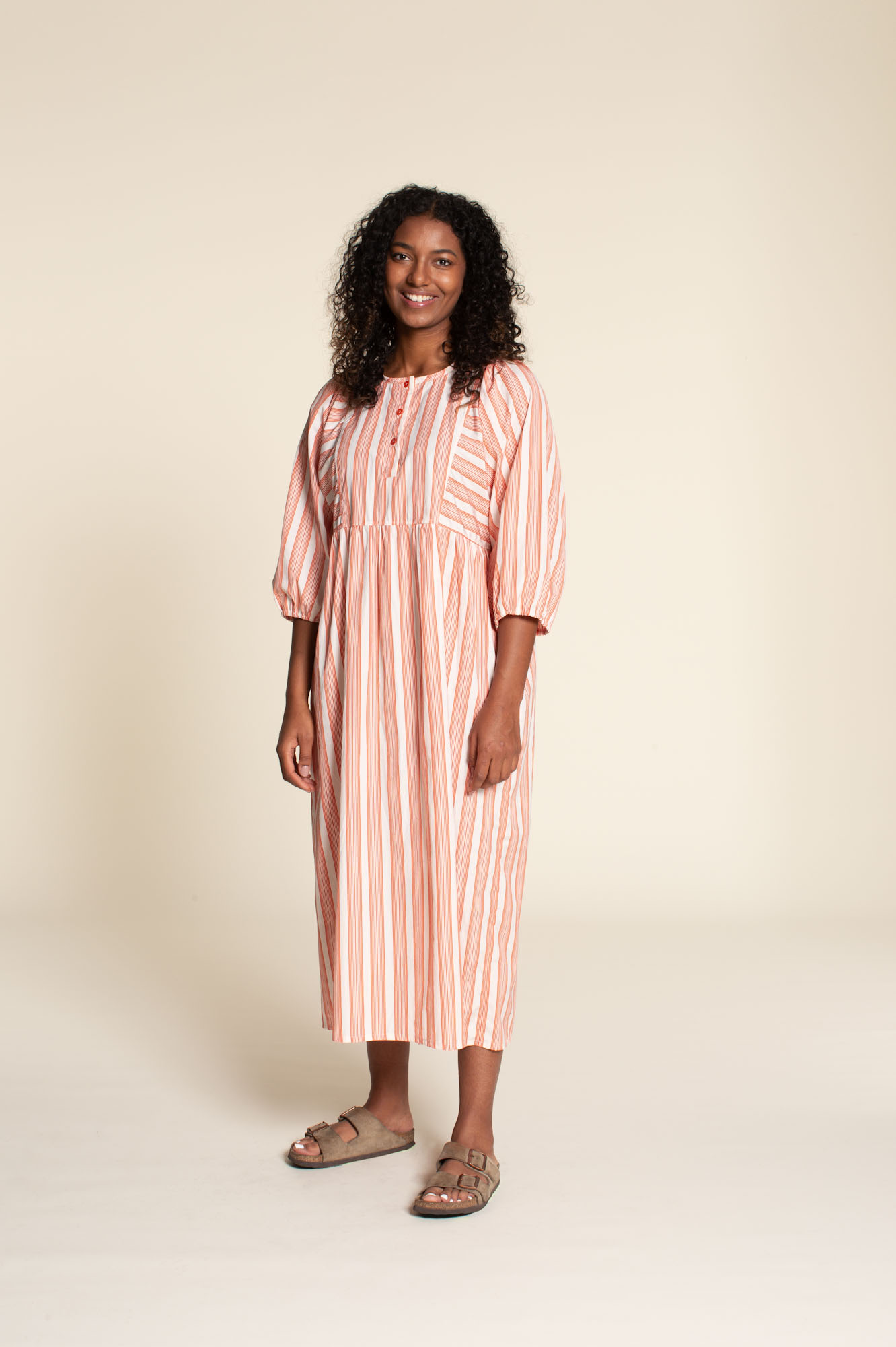 Woman wearing the Balka Dress sewing pattern from Wardrobe by Me on The Fold Line. A dress pattern made in cotton, linen, viscose, or silk fabric, featuring kaftan styling, a button placket, gathered sleeves, a gathered skirt, and side seam pockets.