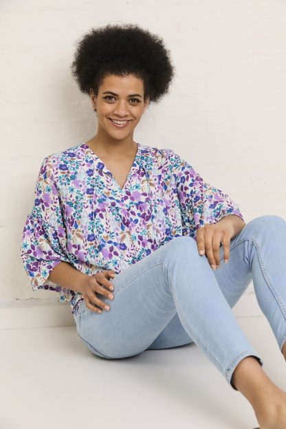 Woman wearing the Hannah Blouse sewing pattern from Atelier Jupe on The Fold Line. A blouse pattern made in viscose, cotton, tencel, linen, or double gauze fabric, featuring a relaxed fit, gathered bodice, wide gathered sleeves, and ties at the neckline.