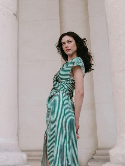 Woman wearing the Judy Dress sewing pattern from Notches on The Fold Line. A dress pattern made in drapey woven or knit fabric, featuring a V-neck, wrap front with ties, short grown-on sleeves, and front slit.