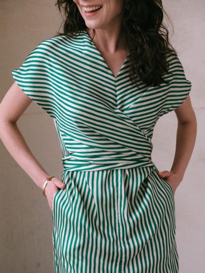 Woman wearing the Judy Dress sewing pattern from Notches on The Fold Line. A dress pattern made in drapey woven or knit fabric, featuring a V-neck, wrap front with ties, short grown-on sleeves, and front slit.