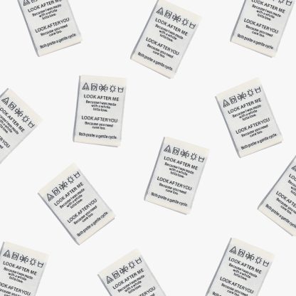 Photo showing 'Look After Me, Look After You' Woven Labels from Kylie & The Machine on The Fold Line. A washable, durable and non-scratchy fabric label featuring an ivory background with black text, they are all ready to be sewn into your handmade clothes.