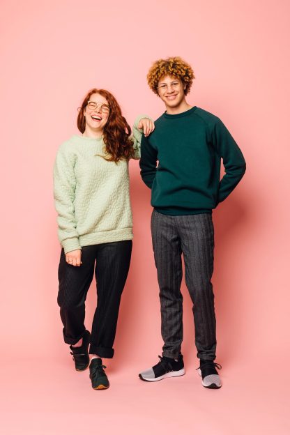 Man and woman wearing the Maggi Sweater sewing pattern from Melilot on The Fold Line. A unisex sweater pattern made in ponte, double knit, sweatshirt fleece, french terry, jersey or sweater knit fabrics, featuring a relaxed fit, raglan sleeves, cuff, neck and hem bands, full length sleeves plus shorter or longer length.