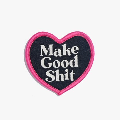 Photo of the ‘Make Good Shit’ iron-on patch from Kylie & The Machine on The Fold Line. A heart-shaped patch with white text on a black background with a pink border ready to be attached to your handmade garment or bag.