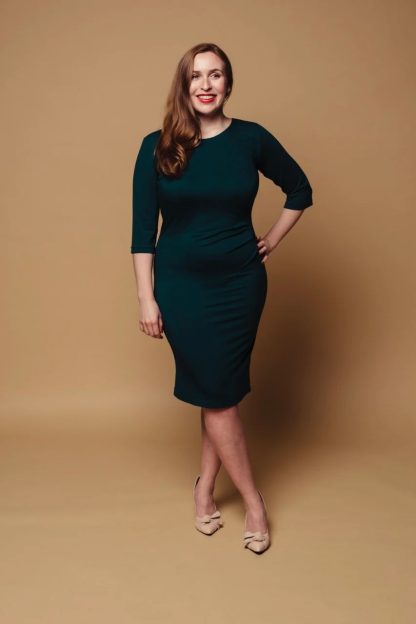 Woman wearing the Runa Dress sewing pattern from Melilot on The Fold Line. A dress pattern made in jersey fabrics, featuring asymmetrical pleats on the side of the front waist, scoop neckline and knee length finish.
