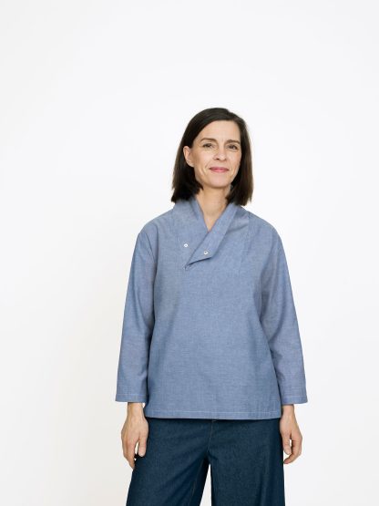 Woman wearing the Unisex Wrap Collar Shirt sewing pattern from The Assembly Line on The Fold Line. A shirt pattern made in light to medium weight fabric, featuring a straight cut, relaxed fit, wrap-around collar with a snap, and bracelet length sleeves.