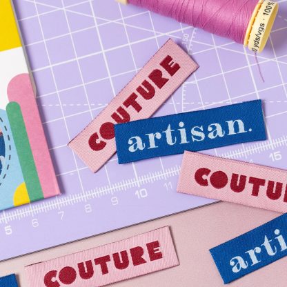 Photo of the 'Couture / Artisan' woven labels from Little Rosy Cheeks on The Fold Line. The pack includes 6 woven labels with a pink or blue background ready to be sewn into your handmade clothes.