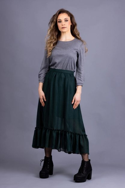 Woman wearing the Ella Skirt sewing pattern from Forget-me-not Patterns on The Fold Line. A gathered skirt pattern made in cotton, viscose/rayon, silk, wool, or linen fabric, featuring a subtle high-low hem finished with a gathered tier, A-line silhouette, side seam pockets, and midi length.
