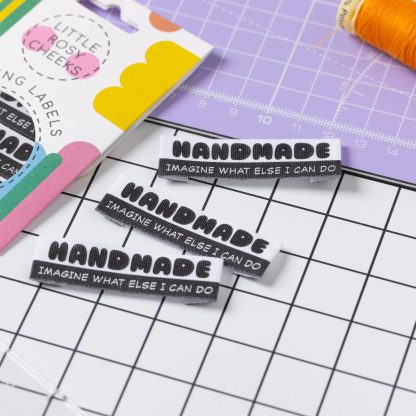 Photo of the 'Handmade - Imagine What Else I Can Do' organic cotton labels from Little Rosy Cheeks on The Fold Line. The pack includes 6 labels with text printed in black on a white background, ready to be sewn into your handmade clothes.