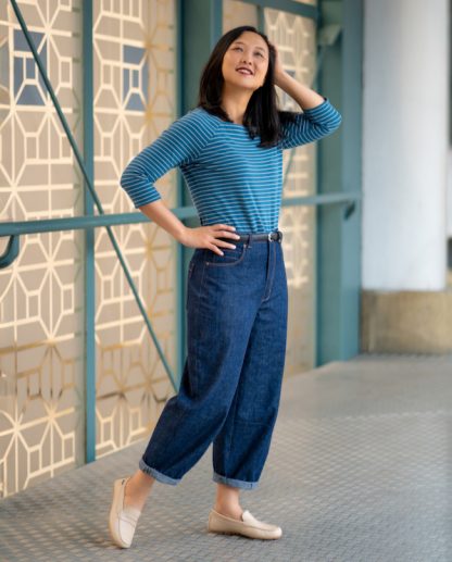 Woman wearing the Belleville Jeans sewing pattern from Itch to Stitch on The Fold Line. A jeans pattern made in denim, twill, or heavyweight linen fabric, featuring a high waist, classic five-pocket styling, a pocket stay, darts at the knees and front hem, barrel leg, and above-ankle length.
