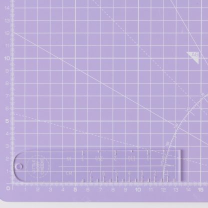 Photo of the Label Placement Ruler from Little Rosy Cheeks on The Fold Line. A transparent acrylic ruler marked in centimetres and inches to achieve sewing label placement perfection.