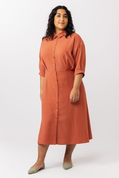 Woman wearing the Silmu Shirt Dress sewing pattern from Named on The Fold Line. A dress pattern made in shirting fabric, featuring an overlapping collar, button front, waist pleats, pleated half sleeves, a tie closure at the back, and midi length.