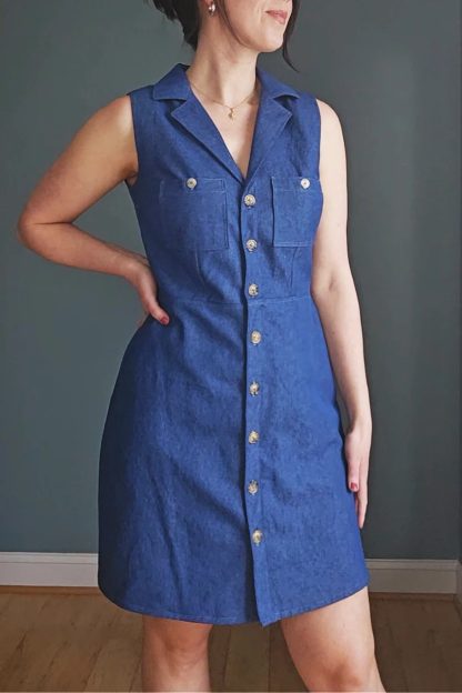 Woman wearing the Vivi Dress sewing pattern from Pattern Scout on The Fold Line. A sleeveless dress pattern made in rayon, linen, denim, twill, or cotton poplin fabric, featuring a notched collar, button front, darts, chest pockets, and mini length.