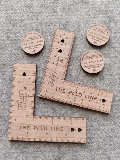 Photo of the Sewing Ruler from Jenerates on The Fold Line. A useful square ruler made in cherry wood veneer and marked in centimetres or inches with cut outs for adding or subtracting seam and hem allowances.